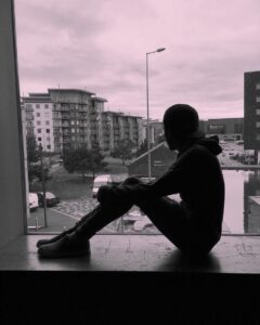 Picture of man sitting on window ledge.